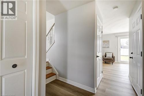 Bright interior hallway featuring wood-finish flooring, white trim, and white paneled doors with matte black hardware - 217 Lawnhurst Court, Hamilton, ON - Indoor Photo Showing Other Room