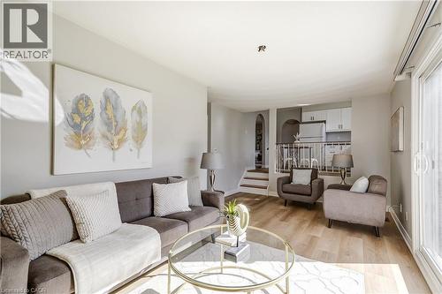 Open-concept living area featuring wood-finish flooring, light grey wall tones, and a sliding glass door - 217 Lawnhurst Court, Hamilton, ON - Indoor Photo Showing Living Room