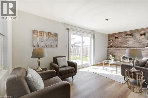 Living area featuring wood-finish flooring and a stone accent wall with built-in shelving - 217 Lawnhurst Court, Hamilton, ON - Indoor Photo Showing Living Room