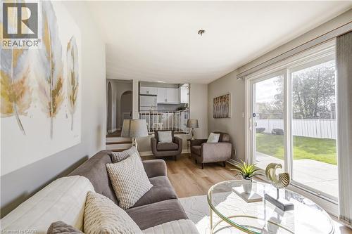 Living area featuring wood-finish flooring, a large sliding glass door opening to the backyard, light-toned wall paint, and recessed ceiling lighting - 217 Lawnhurst Court, Hamilton, ON - Indoor Photo Showing Living Room