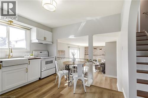 Kitchen featuring white shaker cabinetry, gold-finish hardware, a farmhouse sink, and wood-finish flooring - 217 Lawnhurst Court, Hamilton, ON - Indoor Photo Showing Kitchen