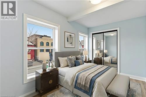 Light blue walls with white trim, wood-finish flooring, white ceiling fixture, and mirrored closet doors - 149 Lottridge Street, Hamilton, ON - Indoor Photo Showing Bedroom