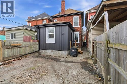Rear exterior featuring a dark gray vertical siding addition, white-framed windows, and a brick main structure - 149 Lottridge Street, Hamilton, ON - Outdoor
