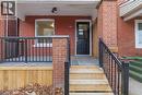 Brick exterior featuring a black front door with glass panels, a covered porch with black metal railings, and a wooden staircase - 149 Lottridge Street, Hamilton, ON  - Outdoor With Exterior 