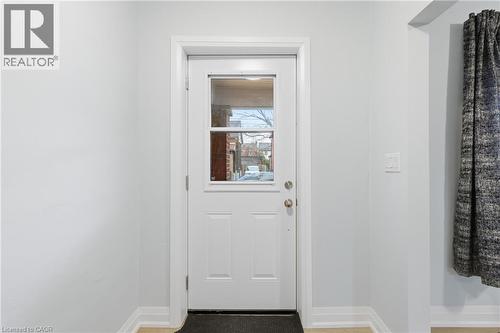 White paneled entry door with clear glass inserts, light grey wall paint, white trim, and wood-finish flooring - 149 Lottridge Street, Hamilton, ON - Indoor Photo Showing Other Room