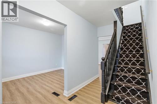 Staircase featuring dark wood newel posts and spindles, carpeted treads with a white and black geometric pattern, and a light wood-finish flooring - 149 Lottridge Street, Hamilton, ON - Indoor Photo Showing Other Room