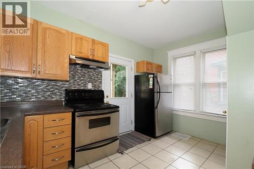 Kitchen featuring wood-finish cabinetry, a mosaic tile backsplash, and ceramic tile flooring - 205 Duke Street E, Kitchener, ON - Indoor Photo Showing Kitchen