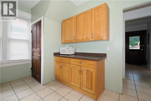 Kitchen area featuring light wood cabinetry with silver-tone hardware, a dark countertop, and light-toned tile flooring - 205 Duke Street E, Kitchener, ON - Indoor