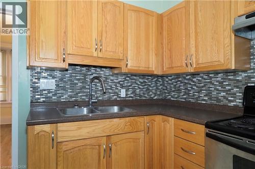 Kitchen featuring light wood cabinetry, a mosaic tile backsplash, and dark countertops - 205 Duke Street E, Kitchener, ON - Indoor Photo Showing Kitchen With Double Sink