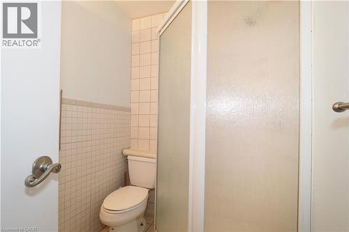 Bathroom featuring a commode, tiled walls, and an enclosed shower with a frosted glass door - 205 Duke Street E, Kitchener, ON - Indoor Photo Showing Bathroom