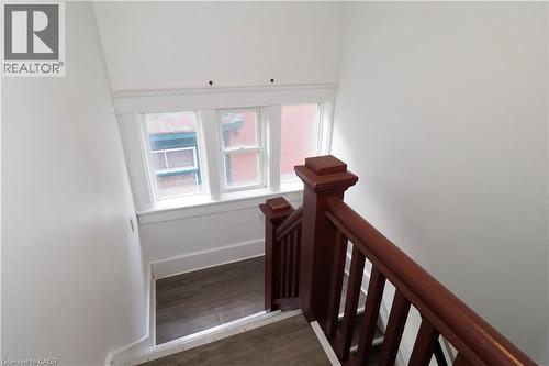 Hardwood staircase featuring a rich mahogany finish and white balusters - 205 Duke Street E, Kitchener, ON - Indoor Photo Showing Other Room
