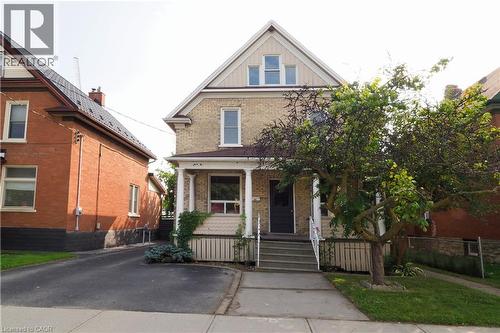Two-story brick exterior featuring a covered front porch with white columns - 205 Duke Street E, Kitchener, ON - Outdoor With Facade