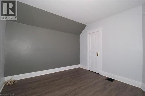 Room featuring wood-finish flooring, white baseboards, and a white panel door with brass hardware - 205 Duke Street E, Kitchener, ON - Indoor Photo Showing Other Room