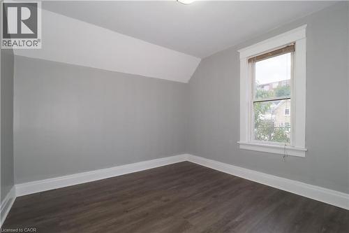 Room featuring wood-finish flooring, a double-hung window with white trim, and light gray wall paint - 205 Duke Street E, Kitchener, ON - Indoor Photo Showing Other Room