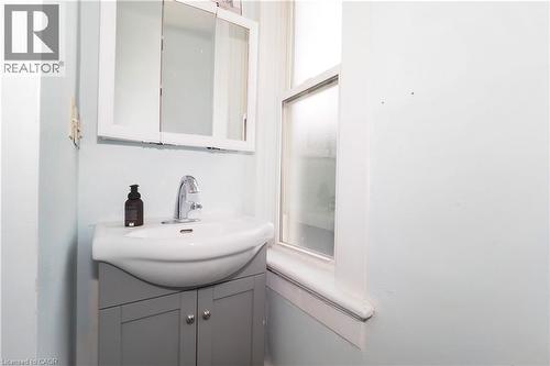 Bathroom vanity featuring a ceramic sink, chrome faucet, and gray cabinet storage - 205 Duke Street E, Kitchener, ON - Indoor Photo Showing Bathroom