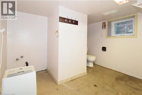 Utility area featuring concrete flooring, a toilet, a window with a security screen, and plumbing hookups for laundry appliances - 205 Duke Street E, Kitchener, ON - Indoor Photo Showing Other Room