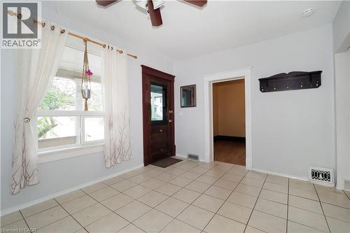 Light-toned tile flooring throughout the space, featuring a dark wood-finish entry door with clear glass paneling - 205 Duke Street E, Kitchener, ON - Indoor Photo Showing Other Room
