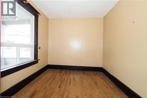 Room featuring wood-finish flooring, dark-stained baseboards, and a large window with white framing - 205 Duke Street E, Kitchener, ON - Indoor Photo Showing Other Room