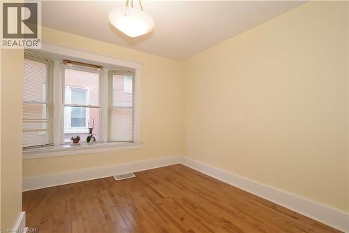 Bright room featuring a three-panel bay window, hardwood flooring, and neutral wall tones - 205 Duke Street E, Kitchener, ON - Indoor Photo Showing Other Room