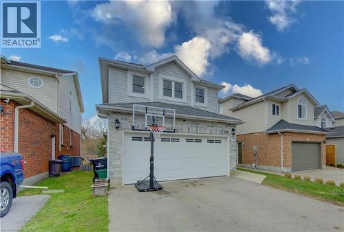Modern residential exterior featuring light-toned siding, a stone facade, and a two-car garage with a white door - 512 Hidden Creek Drive, Kitchener, ON - Outdoor