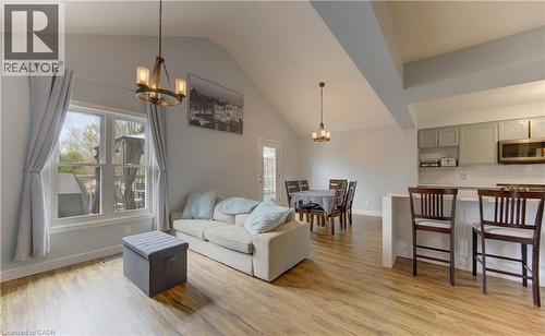 Open-concept living space with vaulted ceilings, wood-finish flooring, a kitchen island with seating, pendant lighting, and a dining area with direct outdoor access - 512 Hidden Creek Drive, Kitchener, ON - Indoor