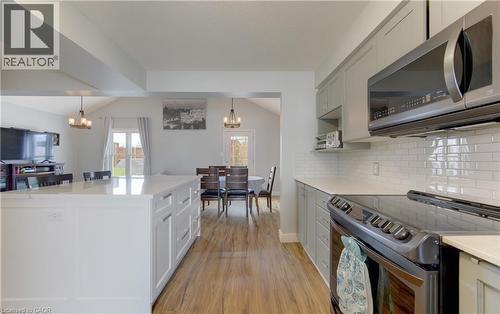 Open-concept kitchen with a white center island featuring integrated storage, light wood-finish flooring, and white subway tile backsplash - 512 Hidden Creek Drive, Kitchener, ON - Indoor Photo Showing Kitchen