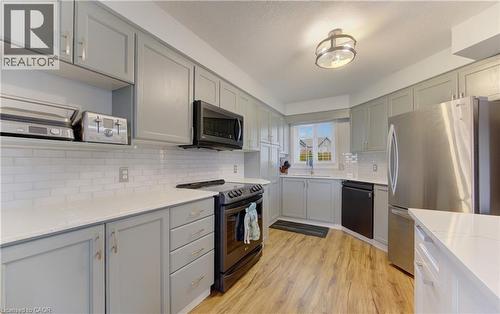 Kitchen featuring light gray cabinetry with brushed nickel hardware, white subway tile backsplash, white countertops, and wood-finish flooring - 512 Hidden Creek Drive, Kitchener, ON - Indoor Photo Showing Kitchen