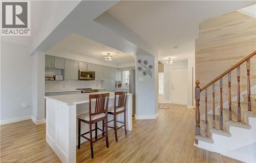 Open-concept kitchen featuring an island with white paneling and a light-toned countertop - 512 Hidden Creek Drive, Kitchener, ON - Indoor Photo Showing Kitchen