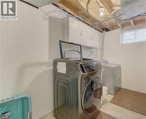 Dedicated laundry area featuring a light gray washer and dryer set, white wall-mounted cabinetry, and a single window with blinds - 512 Hidden Creek Drive, Kitchener, ON - Indoor Photo Showing Laundry Room