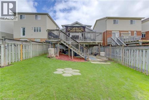 Expansive backyard featuring a manicured lawn, full privacy fencing, and a multi-level wood deck - 512 Hidden Creek Drive, Kitchener, ON - Outdoor With Deck Patio Veranda With Exterior