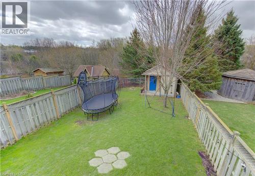 Expansive backyard featuring a manicured lawn, established privacy fencing, a separate storage shed with a blue door, and a circular gazebo structure - 512 Hidden Creek Drive, Kitchener, ON - Outdoor With Backyard