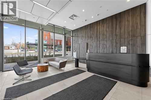 Lobby featuring floor-to-ceiling windows, a dark wood-panel accent wall, and a built-in reception desk - 85 Duke Street W Unit# 507, Kitchener, ON - Indoor Photo Showing Other Room