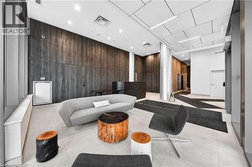Lobby area featuring wood-panel accent walls, light-toned floor tiling, and a geometrically patterned ceiling with integrated lighting - 85 Duke Street W Unit# 507, Kitchener, ON - Indoor Photo Showing Other Room