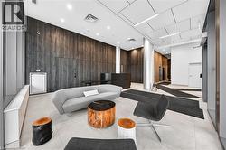 Lobby area featuring wood-panel accent walls, light-toned floor tiling, and a geometrically patterned ceiling with integrated lighting - 