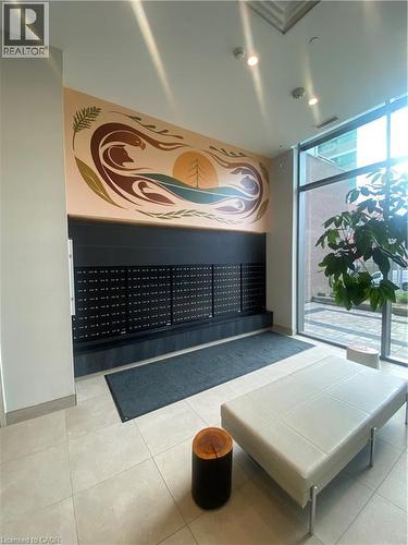 Entry foyer featuring a vibrant wall mural, a built-in mail center with individual compartments, large format tile flooring, and expansive windows - 85 Duke Street W Unit# 507, Kitchener, ON - Indoor Photo Showing Other Room