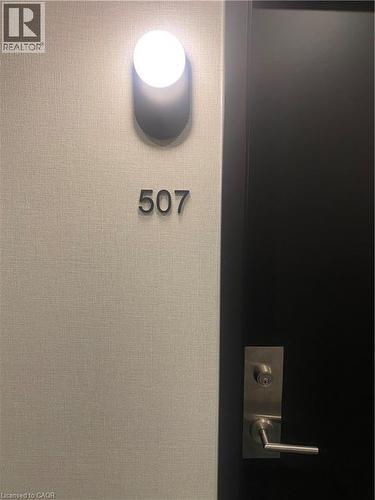 Modern wall sconce illuminating the property number ""507."" Features a textured wall covering, a dark-colored door, and contemporary brushed nickel hardware - 85 Duke Street W Unit# 507, Kitchener, ON -  Photo Showing Other Room