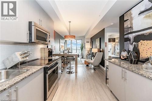 Modern kitchen featuring light gray cabinetry, stainless steel appliances, speckled stone countertops, and a subway tile backsplash - 85 Duke Street W Unit# 507, Kitchener, ON - Indoor Photo Showing Kitchen With Upgraded Kitchen