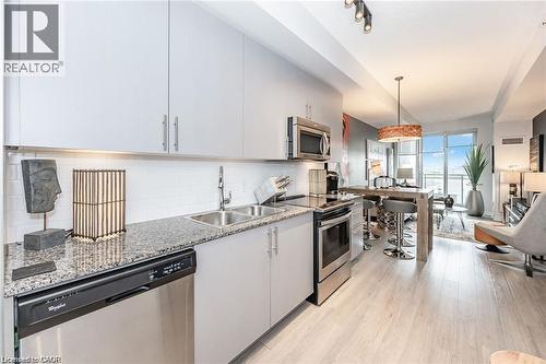 Kitchen featuring light grey cabinetry, granite countertops, and stainless steel appliances including a built-in microwave, range, and dishwasher - 85 Duke Street W Unit# 507, Kitchener, ON - Indoor Photo Showing Kitchen With Double Sink