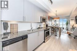 Kitchen featuring light grey cabinetry, granite countertops, and stainless steel appliances including a built-in microwave, range, and dishwasher - 