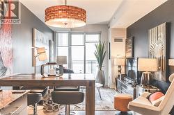 Open-concept living space featuring a wood-finish dining table, dark accent wall, and a large drum pendant light fixture - 