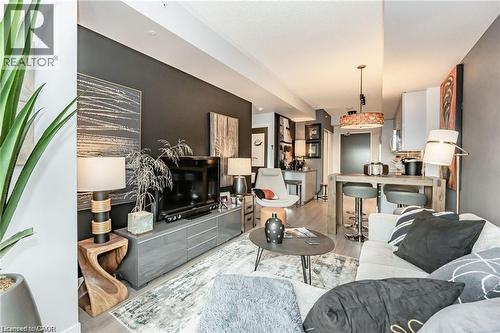 Open-concept living area featuring wood-finish flooring throughout, a dark accent wall, recessed lighting, and a built-in breakfast bar with pendant lighting - 85 Duke Street W Unit# 507, Kitchener, ON - Indoor Photo Showing Other Room