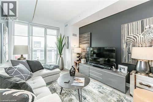Contemporary living area featuring wood-finish flooring and a dark accent wall - 85 Duke Street W Unit# 507, Kitchener, ON - Indoor Photo Showing Living Room
