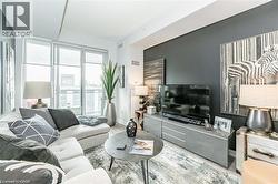 Contemporary living area featuring wood-finish flooring and a dark accent wall - 