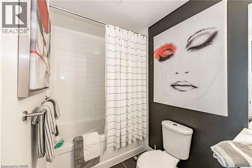 Bathroom featuring a tub/shower combination with white subway tile surround, white toilet, and dark-colored wall accent - 85 Duke Street W Unit# 507, Kitchener, ON - Indoor Photo Showing Bathroom