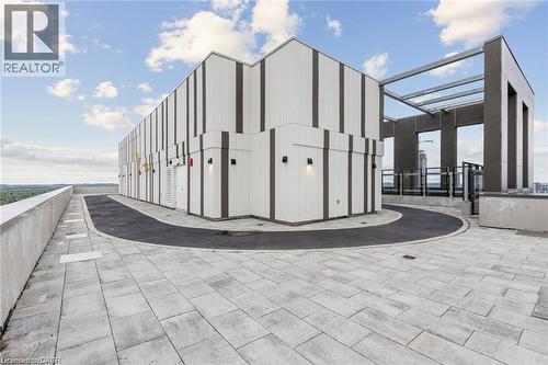 Rooftop terrace featuring light-toned paver flooring, a dark asphalt path, and a concrete perimeter wall - 85 Duke Street W Unit# 507, Kitchener, ON - Outdoor
