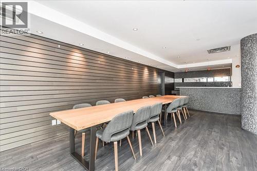 Spacious gathering area featuring wood-finish flooring, a long wooden table, recessed ceiling lighting, and a textured accent wall - 85 Duke Street W Unit# 507, Kitchener, ON - Indoor
