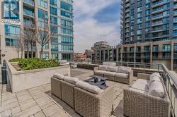 Expansive outdoor terrace featuring paver flooring, a perimeter railing, and concrete planters with mature greenery - 