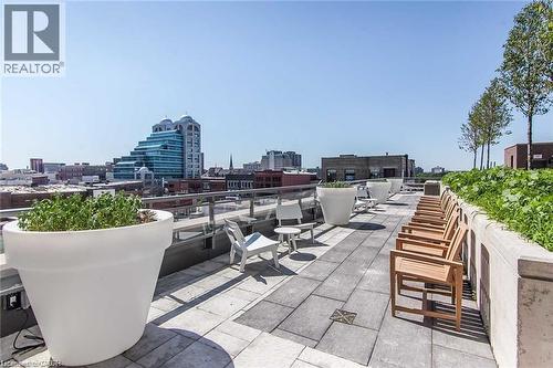 Expansive rooftop terrace featuring large format paver flooring, a glass railing system, and integrated planters with greenery - 85 Duke Street W Unit# 507, Kitchener, ON - Outdoor