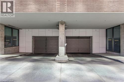 Covered parking garage featuring two roll-up doors and concrete support columns - 85 Duke Street W Unit# 507, Kitchener, ON - Indoor Photo Showing Garage