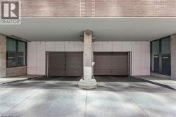 Covered parking garage featuring two roll-up doors and concrete support columns - 